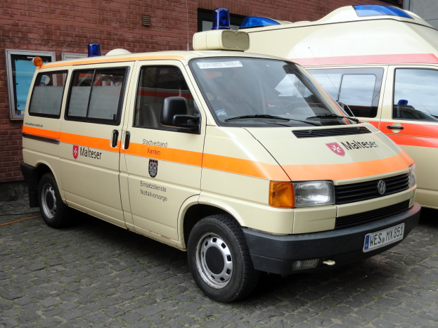 Zwei Rettungswagen nebeneinander vor einem Backsteingebäude mit Fenstern und einer Tür geparkt.