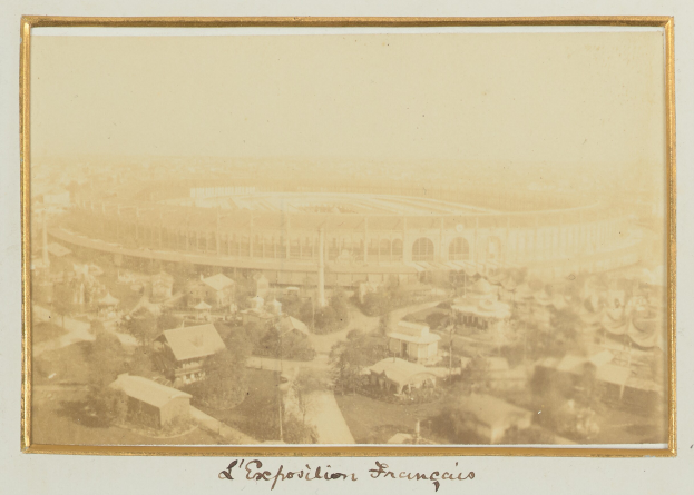 Altes Schwarz-Weiß-Foto eines Stadions in einer städtischen Umgebung, umgeben von Gebäuden, Bäumen und Strommasten mit Text unten.