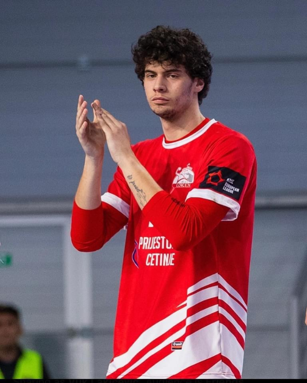 Ein Mann in rot-weißem T-Shirt klatscht in der Vordergrund mit einer anderen Person und einer Wand im Hintergrund, mit Text 'Copenhagen Futsal Club - Foto 1' unten.
