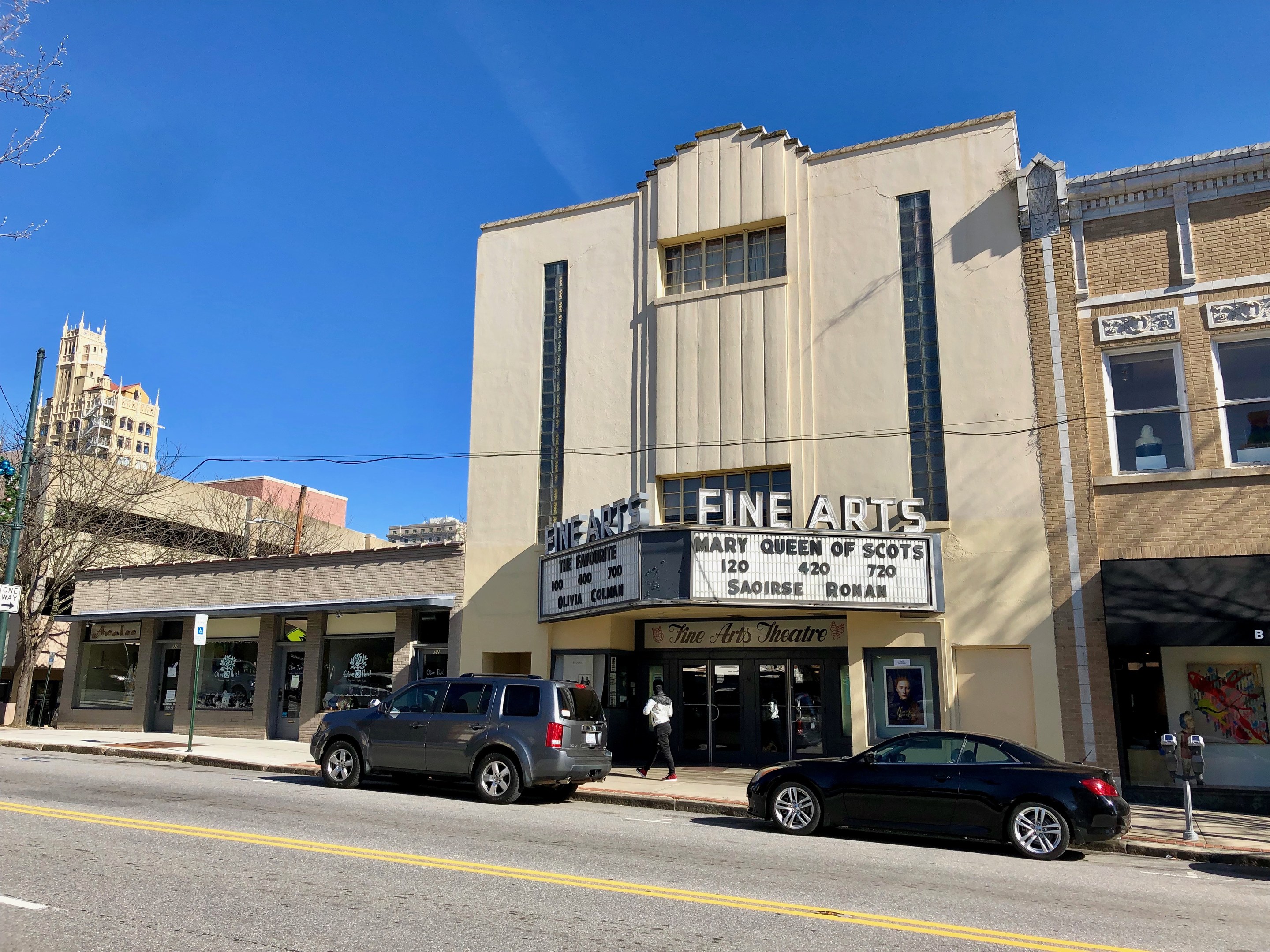 Außenansicht des Feinschmecker-Theaters in St. Louis, Missouri, mit Fahrzeugen auf der Straße, einem Fußgänger auf dem Gehweg, einem Wegweiser, Bäumen, Gebäuden und Himmel.
