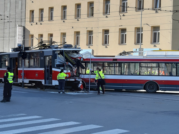 Rote und weiße Straßenbahn krachte auf der Straße mit ein paar Menschen in der Nähe und einem Gebäude im Hintergrund.