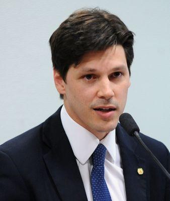 Mann in Anzug und Krawatte spricht in ein Mikrofon an einem Rednerpult, wahrscheinlich zur Genehmigung eines Gesetzes durch die Regierung.