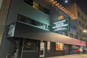 Das Focus Innovation Studio in New York City bei Nacht, mit beleuchteten Gebäuden, Menschen auf dem Bürgersteig und dem Himmel im Hintergrund.