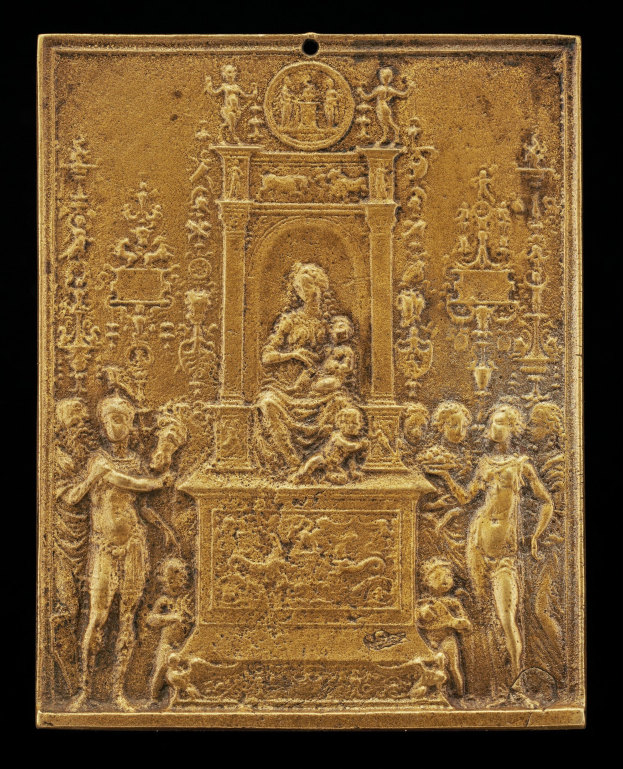 Goldene Plakette mit detaillierter Skulptur einer Frau in einem langen Kleid und eines Mannes in einem Anzug und Krawatte, eingerahmt von einem goldenen Rand, vor schwarzem Hintergrund.
