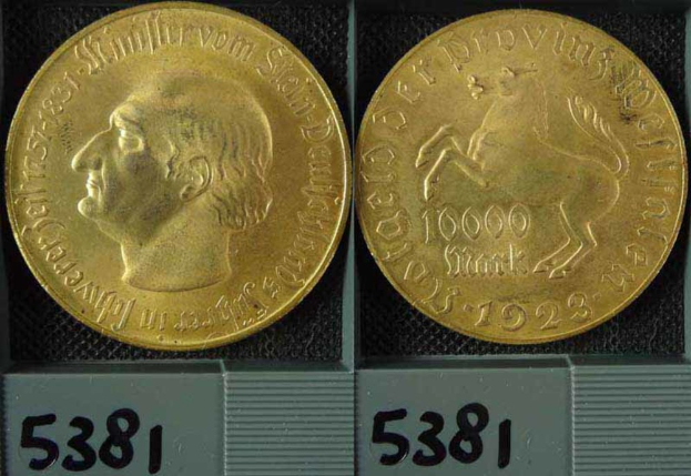 Zwei Goldmünzen in einer Schachtel, eine mit dem Kopf eines Mannes, beide mit Zahlen darauf.
