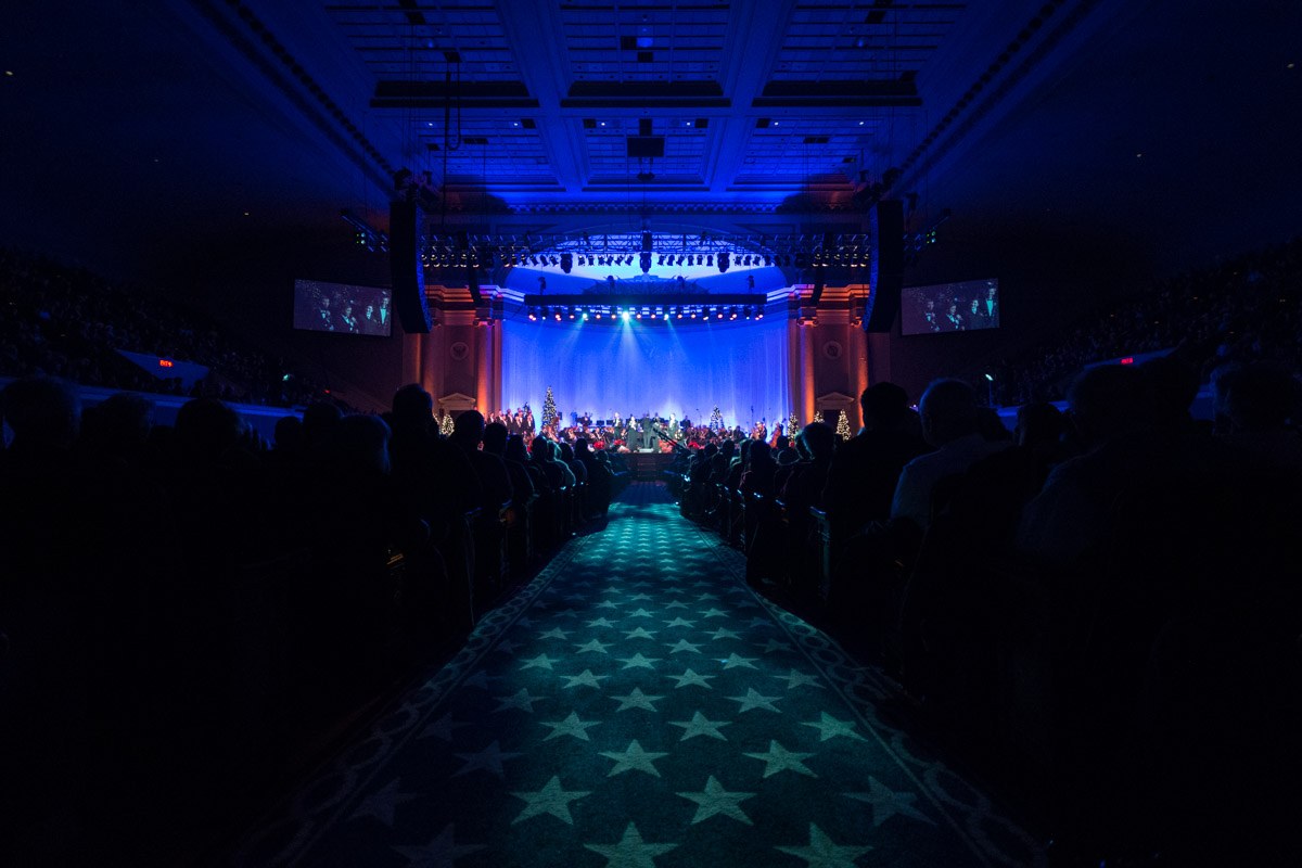 Ein großer Zuschauerraum mit Sitzplätzen, eine Bühne mit Musikern und Deckenbeleuchtung und -fernseher, was auf ein Konzerthaus während der Nationalkonvention 2019 hindeutet.