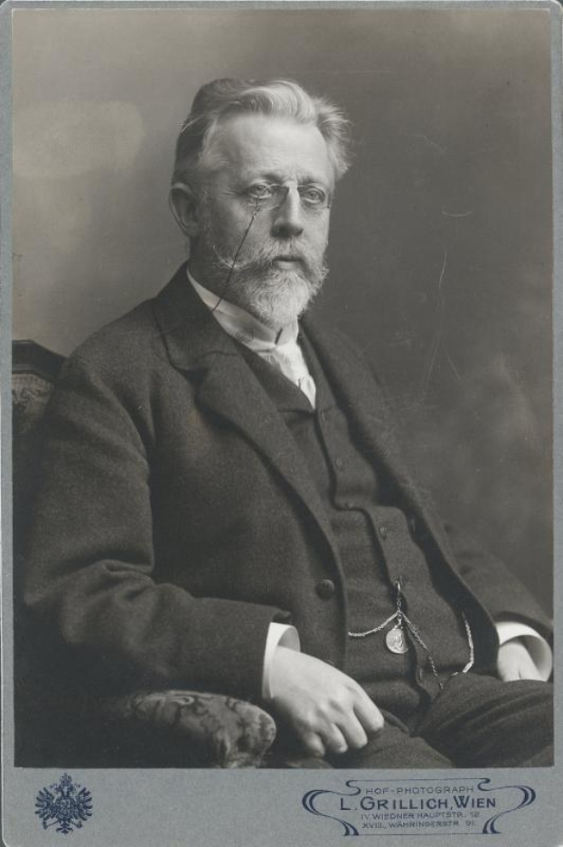 Schwarz-weiß-Fotografie eines bärtigen Mannes mit Brille, der in einem Stuhl sitzt, mit Text unten, der ihn als "L. Grillich Wien, den Gründer der deutschen Revolution" identifiziert.