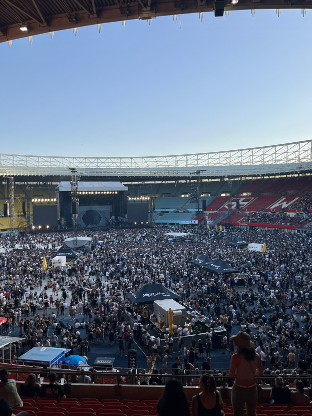 Große Menschenmenge auf Sitzplätzen und Stehplätzen in einem Stadion mit Geländern, Zelten und Deckenbeleuchtung unter einer Dachkonstruktion im O2 Arena in London.