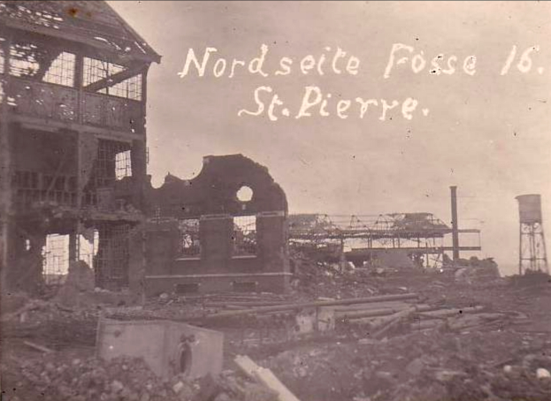 Ein Schwarz-Weiß-Foto eines zerstörten Gebäudes mit einem Turm auf der rechten Seite, gebrochenen Fenstern und Schutt in der Umgebung.